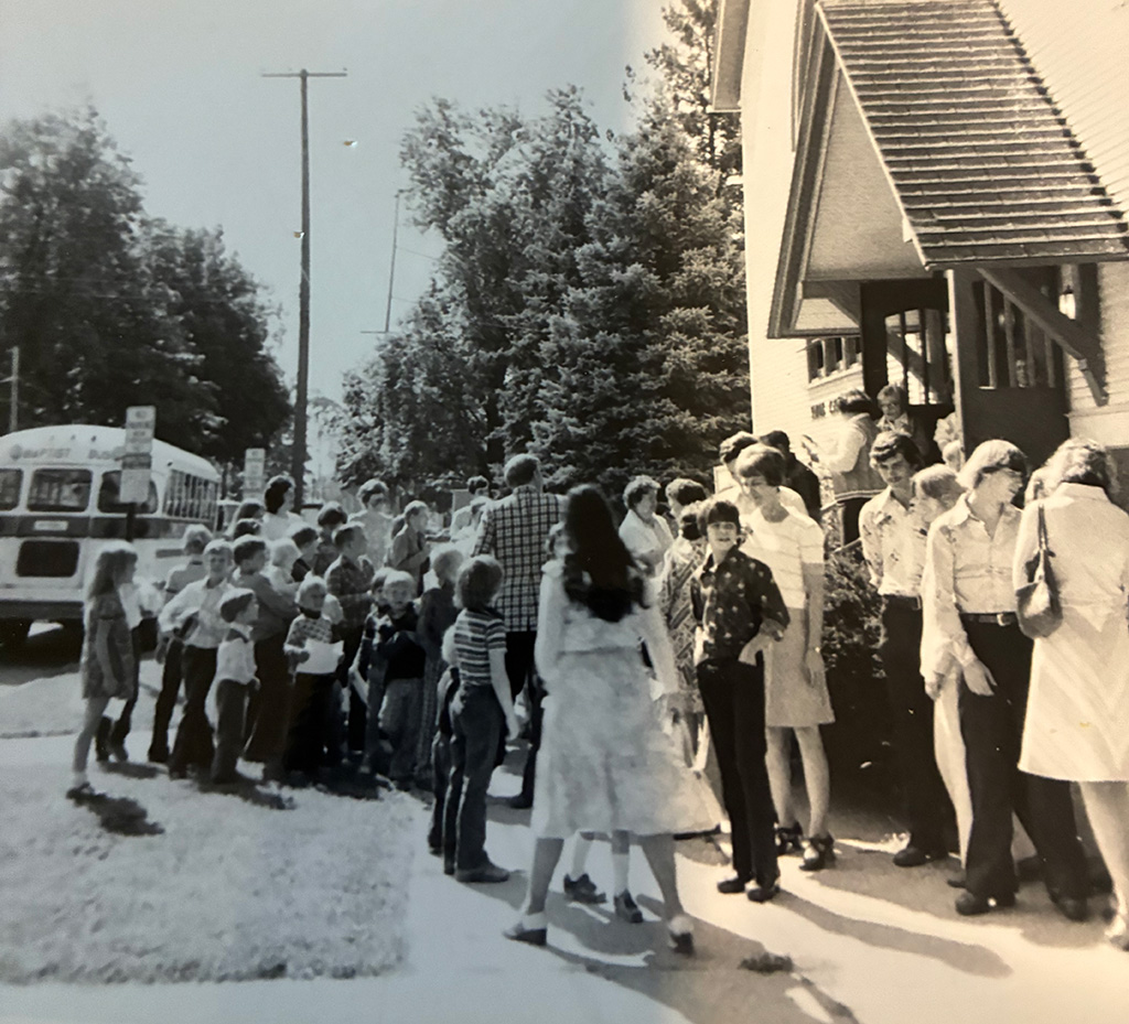 A group gathers in front of a church for Sunday School after riding the bus.